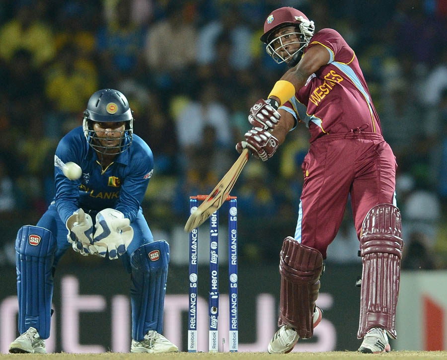 Kumar Sangakkara (L) watches as  West Indies cricketer Dwayne Bravo plays a shot 