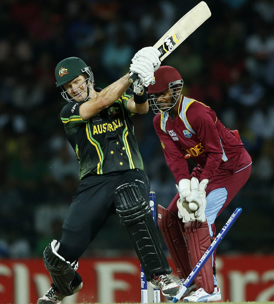 Australia's batsman Shane Watson, left, is bowled out in front of West Indies' wicketkeeper Denesh Ramdin 