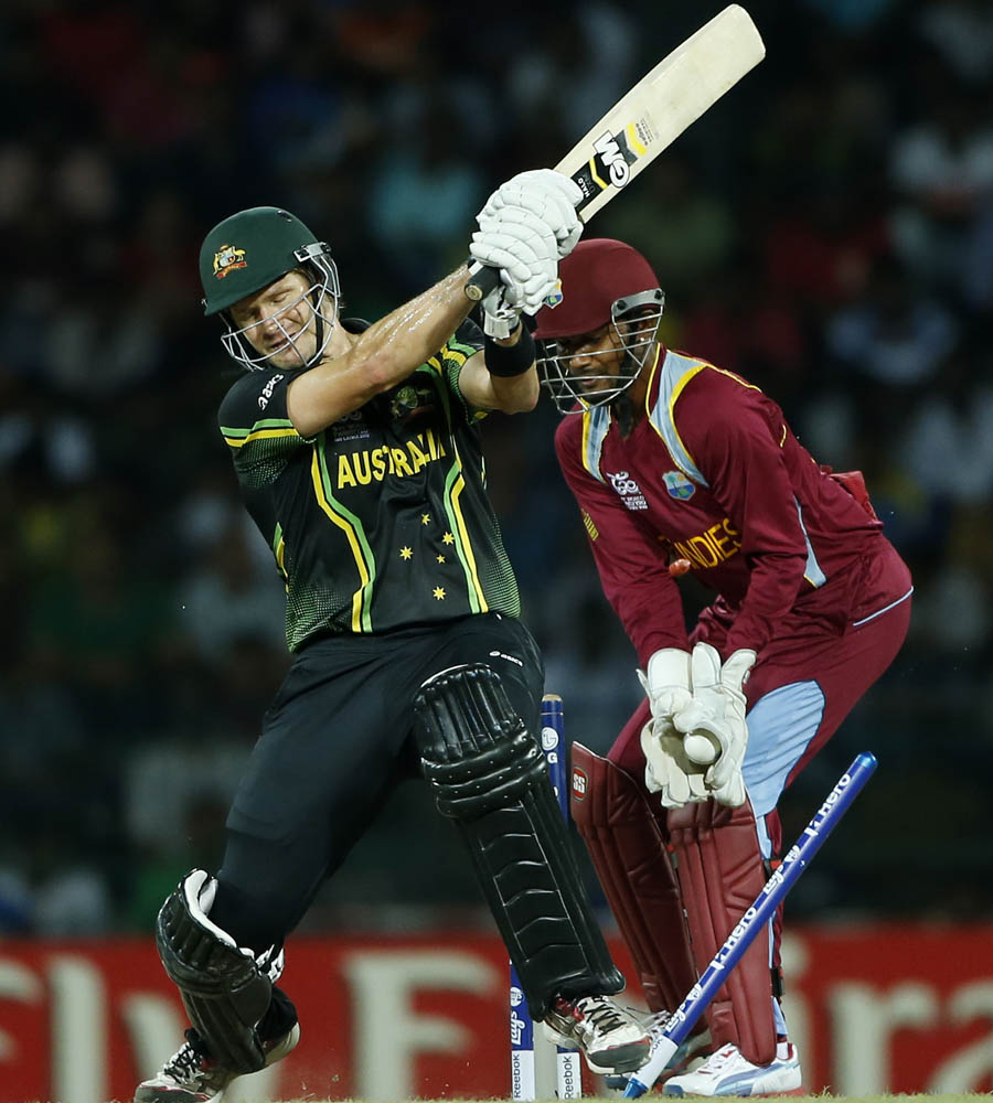 Australia's batsman Shane Watson, left, is bowled out in front of West Indies' wicketkeeper Denesh Ramdin