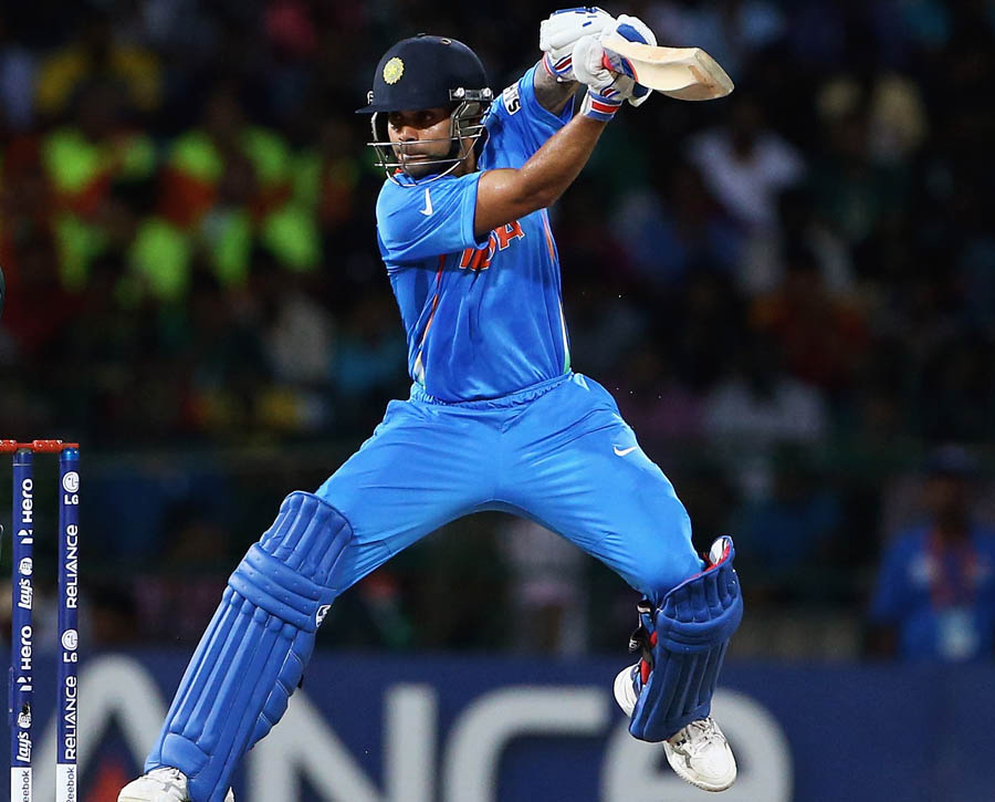 Virat Kohli of India hits the ball towards the boundary, as Kamran Akmal